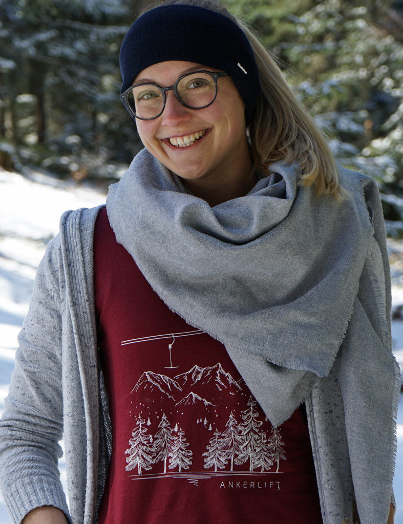 Skifahrerin trägt rotes ANKERLIFT Winterwald T-Shirt im Skiurlaub auf der Skipiste.